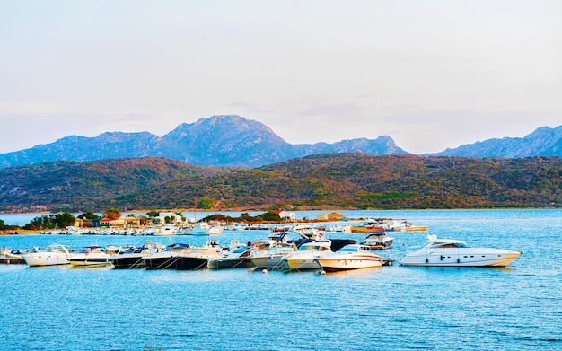 Zonsopgang of zonsondergang met jachten in Porto Rotondo aan de Costa Smeralda aan de Middellandse Zee op het eiland Sardinië in Italië. Boot in Sardegna in de zomer. Landschap van de provincie Olbia. Gemengde media.