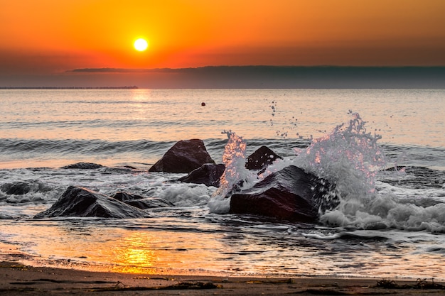 Zonsopgang op het strand met golven spatten