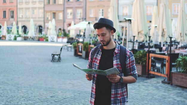 Zoom shot of trendy young tourist with map smiling