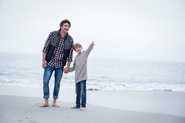 Zoon die terwijl status met vader op zee kust richt