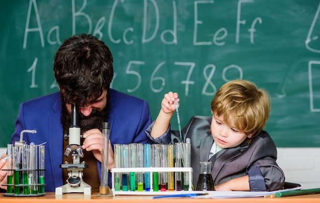 Zoon en vader op school kleine jongen met leraar man wijsheid terug naar school scheikunde en natuurkunde biologie kolf in de hand van de wetenschapper met reageerbuisjes wanneer de understudy is voorbereid