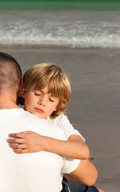 Zoon en zijn vader knuffelen op het strand