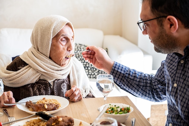 Zoon helpt zijn moeder te eten vanwege een handicap