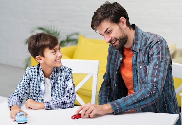 Zoon speelt met speelgoedauto's en kijkt naar zijn vader