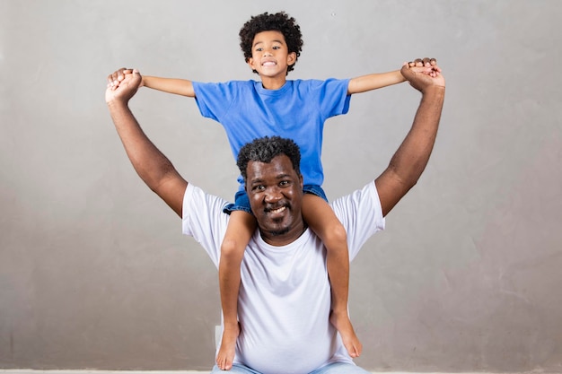 Zoon zittend op vaders schouder op grijze achtergrond Gelukkig afro vader en zoon