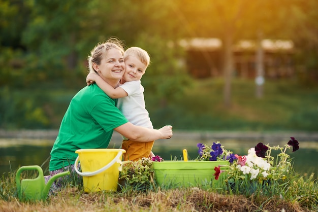 Zorg voor de natuur. Moeder en zoon die zaailing in grond bij de toewijzing op de rivieroever planten. Botanische en ecologie concept.