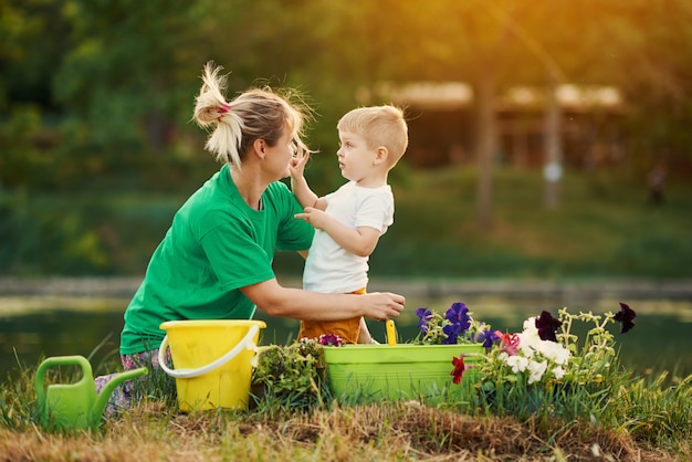 Zorg voor de natuur. Moeder en zoon die zaailing in grond bij de toewijzing op de rivieroever planten. Botanische en ecologie concept.