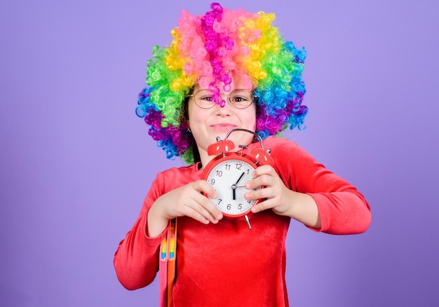 Zorg voor je tijd Het leven is leuk Gelukkige jeugd Gelukkig klein meisje Internationale kinderdag Kinderopvang Gelukkige momenten Kind houd wekker Meisje schattig speels kind draagt krullende regenboogpruik