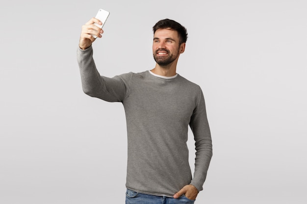 Zorgeloos knappe bebaarde blanke man selfie te nemen op smartphone