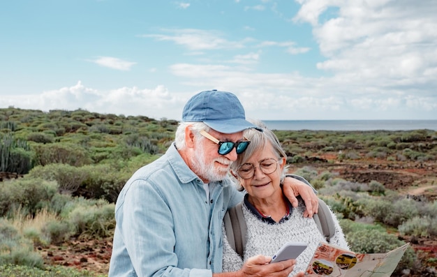 Zorgeloos senior paar wandelen op het platteland kijken naar wandelpaden kaart genieten van de natuur