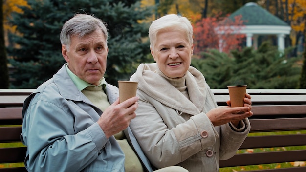 Zorgeloze bejaarde grootouders die hete koffie thee buitenshuis drinken oud paar man vrouw gepensioneerden