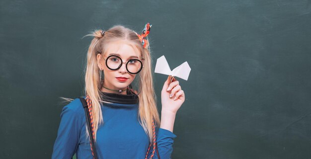 Zorgeloze tiener modieuze blonde meisje schoolbord achtergrond terug naar school stijlvolle scholier