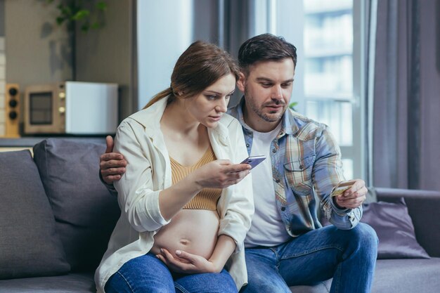 Zorgen Jonge familie zwangere vrouw en echtgenoot met creditcard en telefoon Cheque begrijp het niet Bel de bank