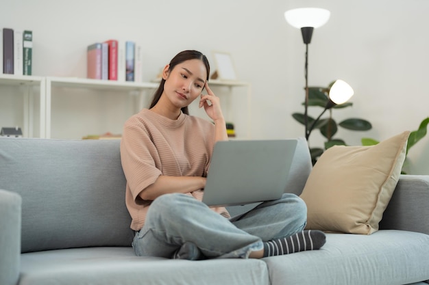 Zorgvuldige jonge vrouw die thuis aan een laptop werkt.