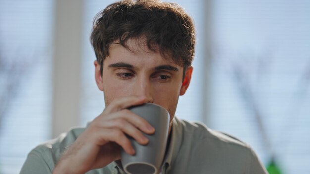Zorgvuldige man drinkt koffie in appartement alleen dichtbij man met kopje thuis
