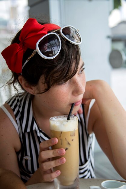 Foto zorgvuldige vrouw die wegkijkt terwijl ze ijskoffie drinkt in een café