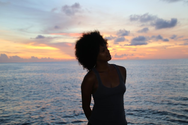 Zorgvuldige vrouw op het strand tegen de hemel bij zonsondergang