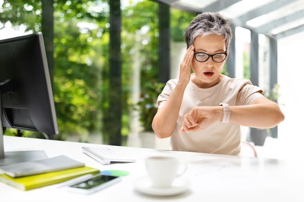 Zorgwekkende angstige volwassen vrouw in casual ondernemer check tijd