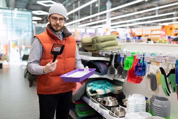 Zorgzame eigenaar kiest een nieuwe kattenbak voor zijn huisdier in een dierenwinkel