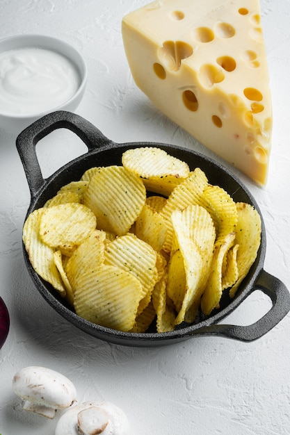 Zoute chips snackset met kaas en ui, met dipsauzen tomaat dip zure room, op witte stenen ondergrond