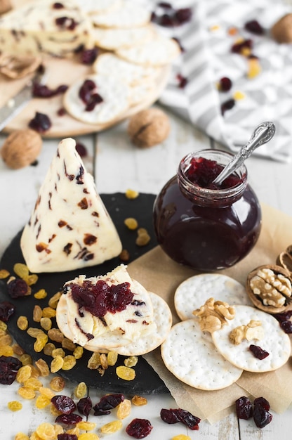 Zoute crackers met zoete cranberrykaas geserveerd met walnootrozijnen, gedroogde cranberry en jam