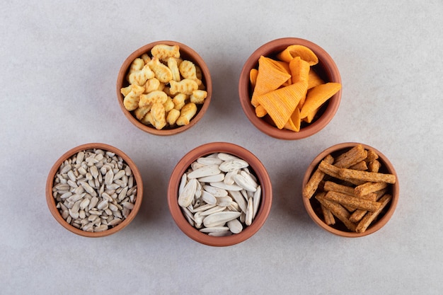 Zoute snacks in kommen op een beige tafel.