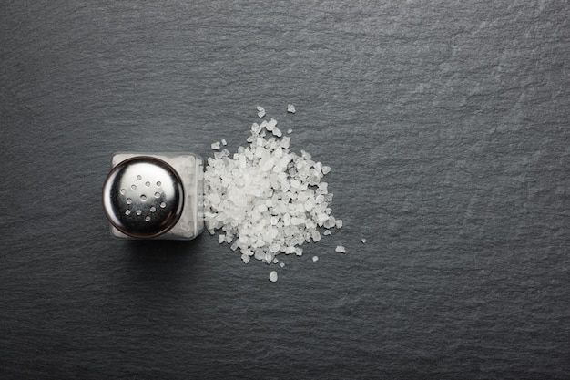 Foto zoutvaatje met wit zout op zwarte steen