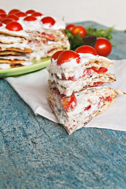 Zucchini cake with tomato and parsley on a blue wooden