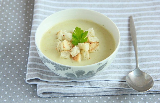 Zucchini cream soup in the bowl with croutons and parsley