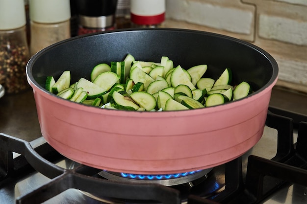 Le zucchine tagliate a semianelli vengono fritte in padella sul fornello a gas