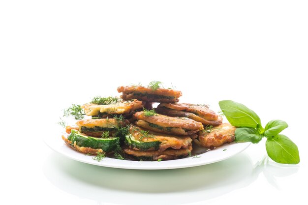 zucchini fried in circles in batter with herbs in a plate isolated on a white background