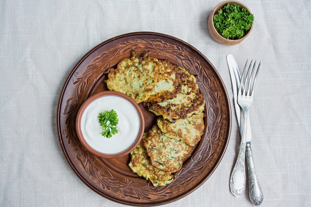 Zucchini fritters, vegetarian zucchini pancakes, served with fresh herbs and sour cream
