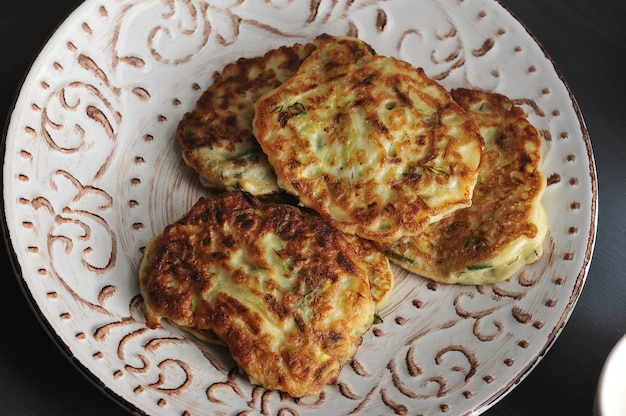 Zucchini fritters with dill on rustic wooden  