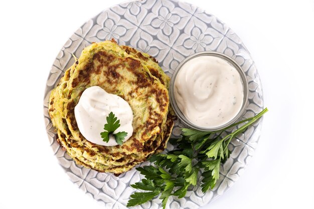 Zucchini fritters with yogurt sauce isolated on white background