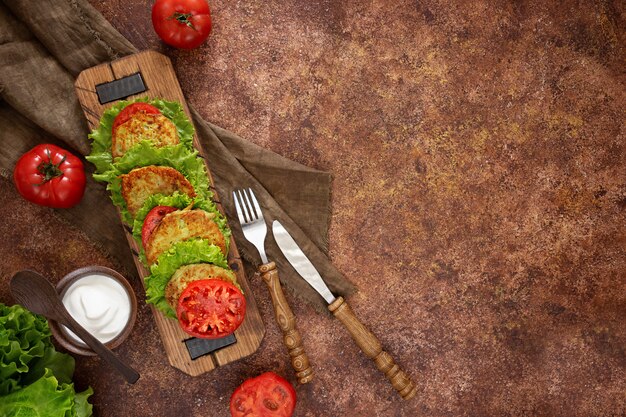 Zucchini pancakes with green salad, fresh tomatoes and sour cream