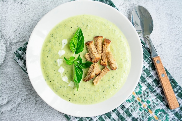 Zucchini puree soup with breadcrumbs on a white textured background