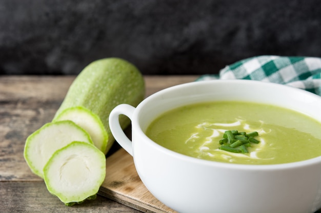 zucchini soup in bowl on wooden table and black