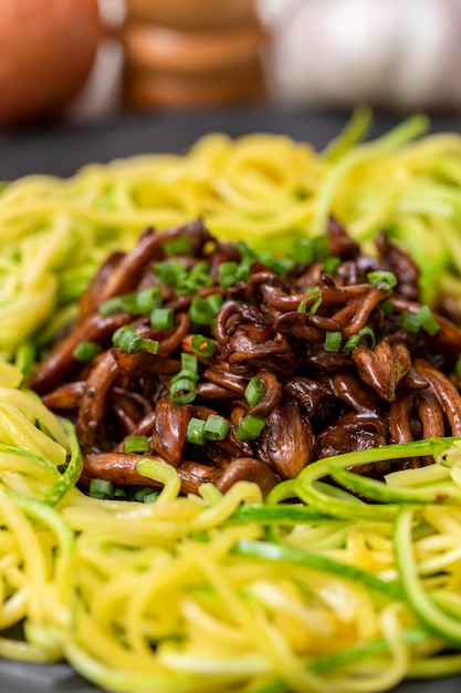 Spaghetti di zucchine con shimeji su lastra di pietra nera.