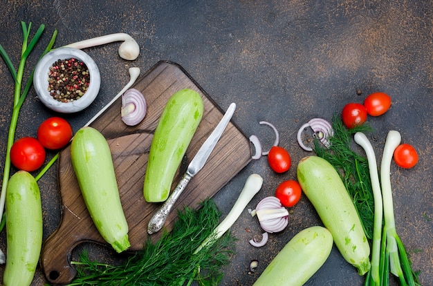 zucchini, tomatoes, herb and spices on black background. Background layout with free text space.