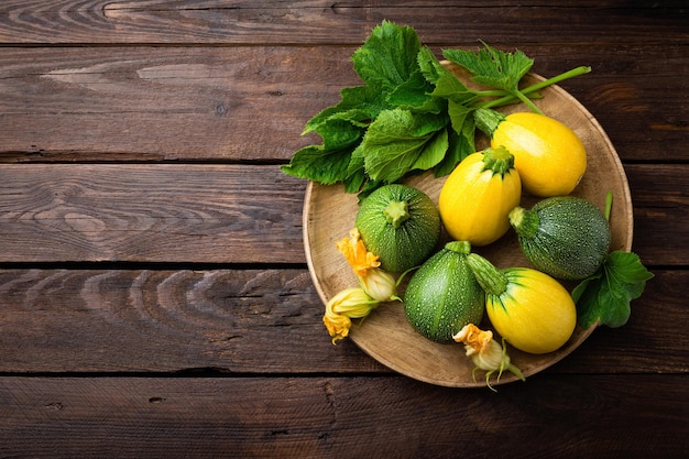 Foto zucchine con foglie e fiori su fondo rustico in legno scuro