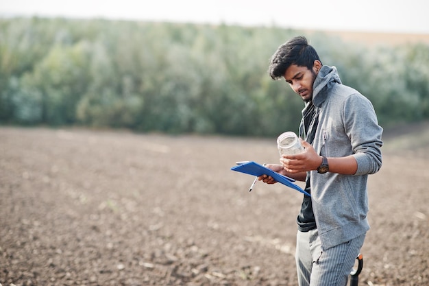 Zuid-Aziatische landbouwkundige boer met schop die zwarte grond inspecteert Landbouwproductieconcept