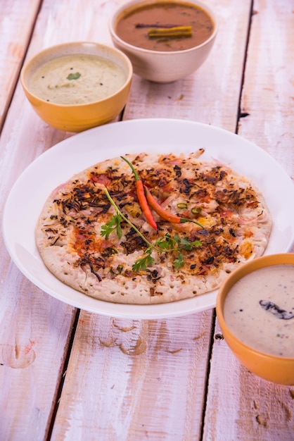 Zuid-Indiaas eten Uttapam of oothappam of Uthappa is een dosa-achtig gerecht gemaakt door ingrediënten in een beslag te koken, geserveerd met kokoschutney, groene chutney en sambar