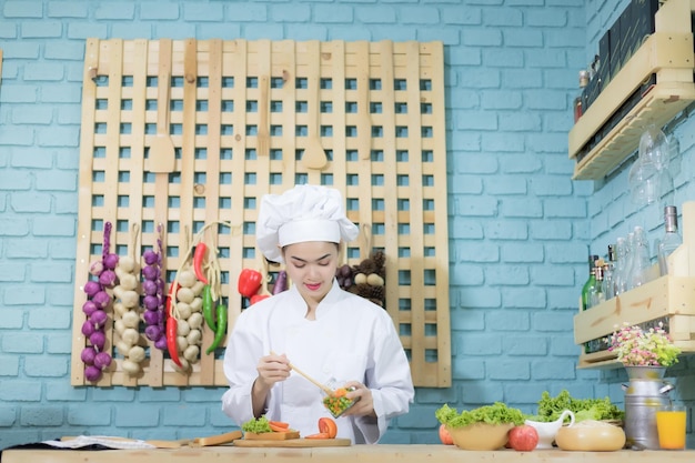 Zuidoost-Aziatische vrouwelijke chef-kok Thai Ze droeg een witte jurk en hoed Ze kookt in de keuken