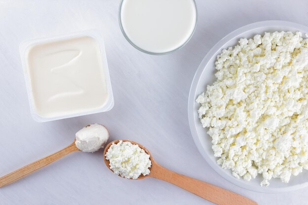 Zuivelproducten op witte achtergrond Cottage cheese room en zachte kaas voor broodjes Houten bestek