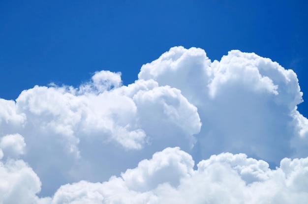 Zuivere witte pluizige cumuluswolken op levendige zonnige blauwe lucht