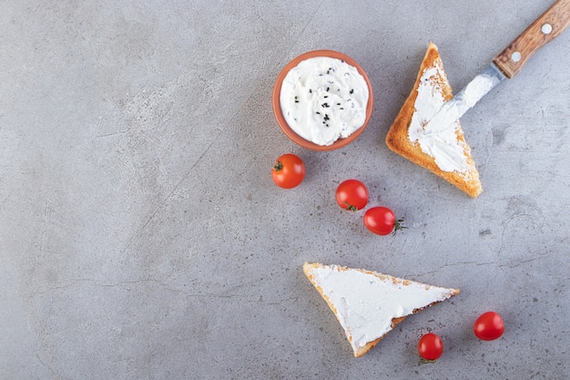 Zure room, kerstomaatjes en toastbrood op stenen tafel.