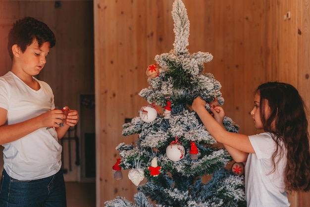 zus en broer versieren een kerstboom thuis