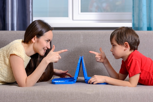 Zus en jongere broer, speel een slagschip, ga op de bank in de kamer liggen en kijk elkaar recht aan.