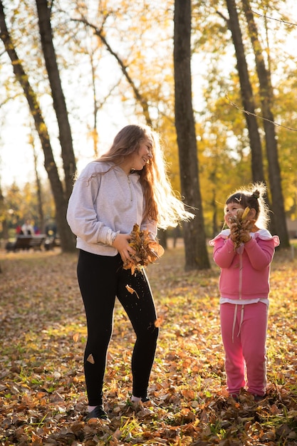 Zusters die oranje bladeren houden in het herfstpark