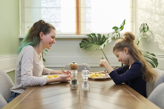 Zusters eten lunch zittend aan tafel in huis keuken